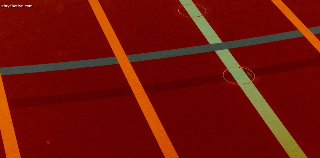 A sports court with intersecting lines in orange and blue, creating geometric patterns on a reddish-brown surface.